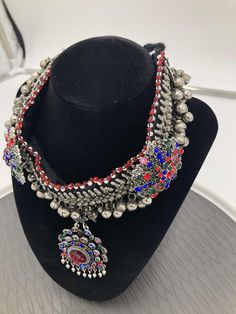 * This chunky kuchi Afghani necklace is embellished with multicolour glass stones, metallic weaving technique, and a dangling floral shaped pendant. The handmade craft is flaunting all the traditional vibes, along with a rusty silver tone. You can pair this exclusive piece with any traditional attire, as well as it would get along with any of your trendy outfits to add a pinch ethnic touch into your fashion statement. Note: The product is handmade, so slight change might occur in the actual prod Multicolor Metal Necklaces For Celebration, Bohemian Jeweled Beaded Necklaces, Bohemian Jeweled Necklace For Celebration, Bohemian Adjustable Jeweled Necklace, Adjustable Jeweled Bohemian Necklace, Bohemian Jeweled Adjustable Necklace, Bohemian Multicolor Jeweled Jewelry, Bohemian Jeweled Necklaces For Party, Bohemian Heavy Multicolor Necklaces