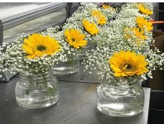 three clear vases filled with yellow and white flowers