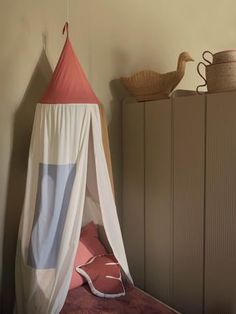 a teepee tent sitting on top of a bed next to a dresser and basket