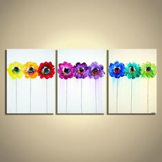 three colorful flower paintings hanging on a wall