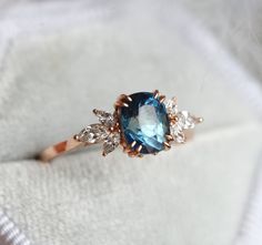 a blue and white diamond ring sitting on top of a white cloth