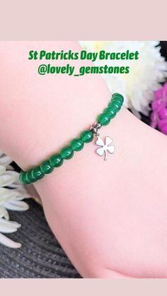 a close up of a person's foot wearing a green bracelet with a clover charm