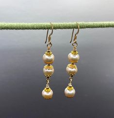 Unique presentation of peach freshwater pearls, antique gold spacers, and filigree bead caps in these elegant dangle earrings. The dangles are connected to each other and to the gold filled earwire through gold filled wrapped loops.  The earrings are about 1 1/4 inches long, measured from the earwire, and come nestled comfortably on a bed of cotton in a white cardboard box. Made in the USA by me. NA-821-0624-1111 Elegant Rose Gold Earrings With Dangling Beads, Delicate Gold Pearl Chandelier Earrings, Pearl Earrings With Gold Beads For Gift, Gold Pearl Chandelier Earrings Delicate Style, Gold Pearl Chandelier Earrings In Delicate Style, Gold Beaded Drop Earrings For Formal Occasions, Pearl Drop Earrings With Gold Beads, Delicate Gold Chandelier Earrings With Pearl Drop, Gold Pearl Bead Earrings For Formal Events