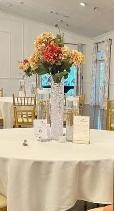 there is a vase with flowers in it on top of a table at a wedding