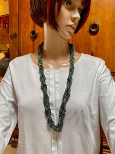 Two strands, each beaded individually and made up of 10 strands each.  The two large strands are then wrapped around each other.  Shades of green wit a bit of purple. Lobster claw clasp. Necklace can be worn long or wrapped are the neck twice as a choker.  Total length : 30" Width 1" Green Double Strand Beaded Necklace, Handmade Green Beaded Lariat Necklaces, Handmade Green Lariat Beaded Necklace, Green Multi-strand Hand-strung Beaded Necklaces, Green Multi-strand Hand-strung Necklaces, Adjustable Green Double Strand Beaded Necklace, Handmade Green Multi-strand Beaded Necklaces, Handmade Green Multi-strand Beaded Necklace, Adjustable Green Handwoven Necklace