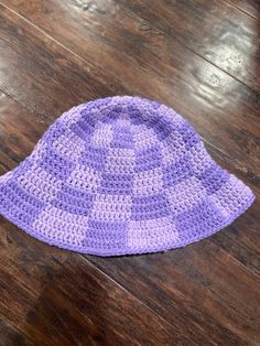 a purple crocheted hat sitting on top of a wooden floor next to a table