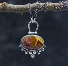 This pendant features a Agua Nueva agate. It's a phenomenal stone, which is rather hard to find in this quality lately. the color and pattern are top notch and so beautiful. It has a hinged bail and sweet ruffle of silver ball details. Flip the pendant over and I have textured the metal with a pattern that mimics the pattern in the stone. The piece is just over 1 inches wide and 1 3/4 inches long ♦Chain: This comes on a oval link chain that is currently 18-20 inches. It has a lobster claw clasp Luxury Agate Round Pendant Necklace, Luxury Metal Cabochon Jewelry, Luxury Cabochon Pendant Gemstones, Modern Silver Jewelry Pendant, Luxury Artisan Oval Pendant Jewelry, Raw Jewelry, Sterling Silver Gemstone Necklace, 2024 Jewelry, Silver Necklace Designs