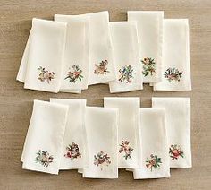 twelve white napkins with embroidered flowers on them