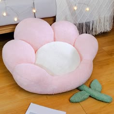 a pink flower shaped pillow sitting on top of a wooden floor