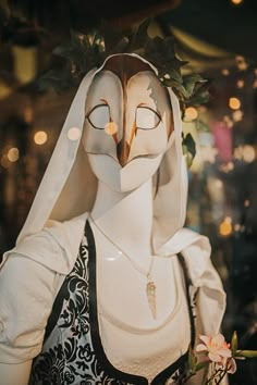 an owl statue wearing a white veil and holding a flower in it's mouth