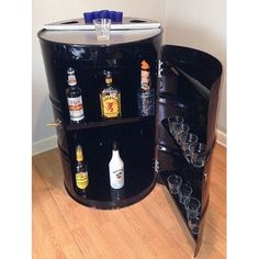 a black barrel with liquor bottles and shot glasses on it's side is shown