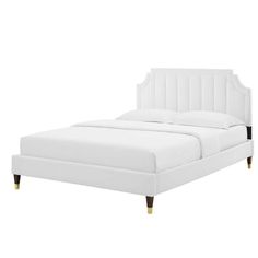 a white bed with wooden legs and headboard in the shape of a tuxedo