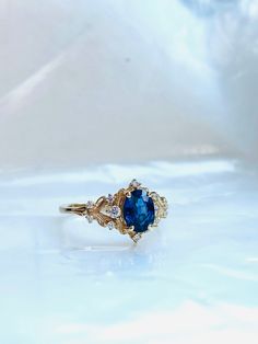 an oval blue sapphire and diamond ring sits on a white surface