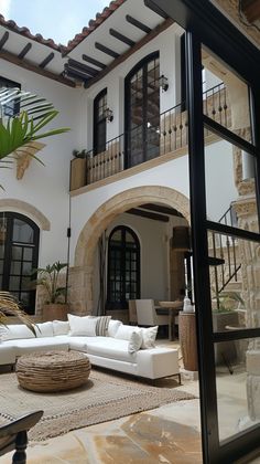 a large white couch sitting in front of a living room next to a building with lots of windows