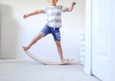 a young boy is standing on a rocking horse in the living room with white walls