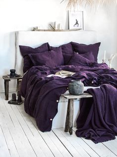 a white bed with purple sheets and pillows