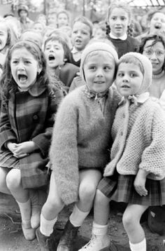 a group of children sitting next to each other in front of a crowd with their mouths open