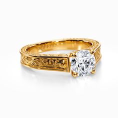 a yellow gold engagement ring with a round diamond in the center and filigrees