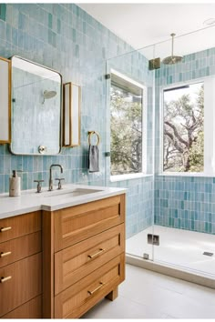 a bathroom with blue tiled walls and wooden cabinetry next to a bathtub in the corner