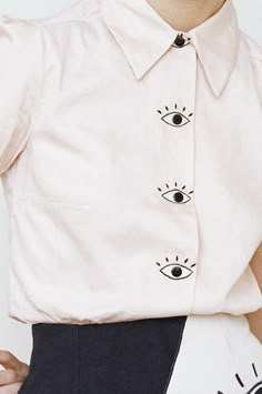 a close up of a person wearing a white shirt with eye patches on the front