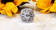 a diamond ring sitting on top of a marble table next to yellow and white flowers