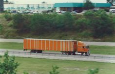 an orange semi truck driving down the road