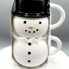 a coffee cup with a snowman on it's side and a black hat on top