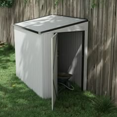 a white shed sitting in the grass next to a fence