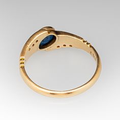 This sleek and low-profile ring is centered with one (1) oval mixed cut natural sapphire in a bezel setting. The shoulders of the ring are each accented with three (3) bead set round brilliant cut diamonds and give the ring a bypass feeling to the design. The ring measures 7.2mm at the top, rises 3.2mm above the finger, tapering to 2.2mm wide and 1.0mm thick at the base of the shank. It is stamped '072 14k 003' and crafted in 14k yellow gold, currently fitting a size 7.5 with easy resizing to make it a unique engagement ring or right hand ring. Heirloom Oval Sapphire Three-stone Ring, Elegant Oval Cabochon Birthstone Ring With Bezel Setting, Modern Oval Sapphire Promise Ring, Classic Oval Sapphire Ring With Rose Cut Diamonds, Gold Sapphire Ring With Oval Tension Setting, Gold Sapphire Ring With Tension Setting And Oval Shape, Timeless Oval Ring With Bezel Setting, Elegant Oval Topaz Ring With Tension Setting, Oval Yellow Gold Sapphire Ring With Bezel Setting