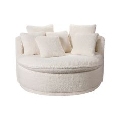 a white round couch with lots of pillows on it's back and side ends