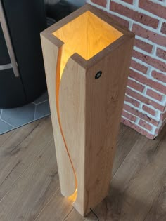 a wooden light box sitting on top of a hard wood floor next to a brick wall