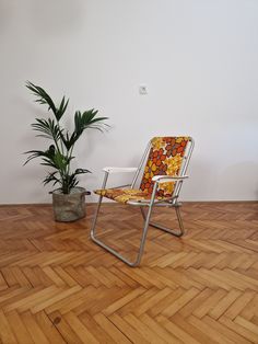 a chair sitting on top of a hard wood floor next to a potted plant