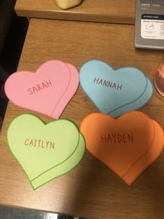 four hearts with names on them sitting on a table next to a laptop computer and money