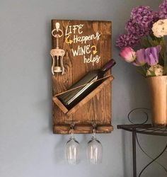 a wooden sign with wine glasses and bottles on it next to a potted plant