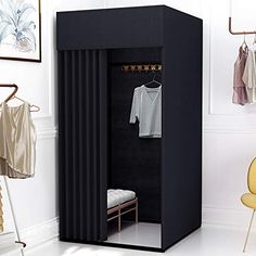 an open black wardrobe with clothes hanging on hooks and two yellow chairs in the background