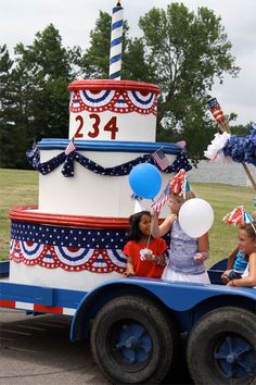 children are riding in the back of a truck decorated for fourth of july with balloons and streamers