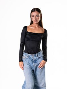 a woman in jeans and a black top posing for the camera with her hands on her hips