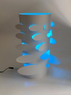 a tall white vase with blue lights on the top and bottom, in front of a white background