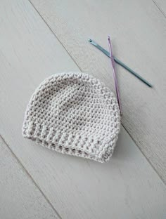 a crocheted hat and knitting needles laying on the floor