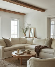 a living room filled with furniture and a round coffee table in front of two windows