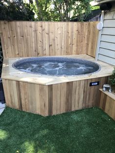 a hot tub sitting in the middle of a yard next to a wooden fence and green grass