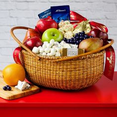 a wicker basket filled with assorted fruit and snacks next to a cutting board