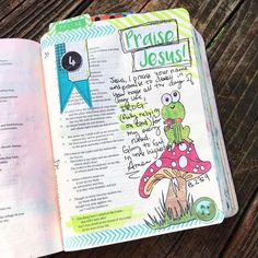 an open bible with the words praise jesus on it and a frog sitting on top of a mushroom