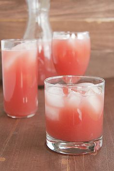 two glasses filled with liquid sitting on top of a wooden table