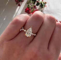 a woman's hand holding a yellow and white diamond ring in her left hand