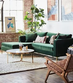 a living room with green couches and paintings on the wall above them, along with a coffee table