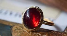 The Classic Dragon Breath Vintage Ring features a mesmerizing deep red garnet stone that captures the light with every turn. Set in a classic gold band with delicate beaded detailing, this ring exudes a timeless elegance. The rich crimson hue of the garnet adds a bold pop of color, making it a striking accessory for any occasion. Perfect for those who appreciate vintage-inspired pieces with a modern twist, the Classic Halo Vintage Ring is designed to enhance your look with a touch of sophistication and charm. Details Classic Halo Vintage Ring in Red Gold pleated Adjustable opening Missy Jewelry Dragon Breath Collection Elegant Red Ruby Ring, Elegant Red Cabochon Jewelry, Classic Red Ruby Ring, Oval Cabochon, Wedding Garnet Cabochon Jewelry, Classic Red Ruby Ring With Oval Cabochon, Elegant Red Cabochon Ruby Ring, Elegant Red Jewelry With Cabochon, Timeless Red Ring As A Gift, Red Garnet Rings With Polished Finish