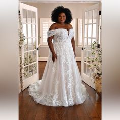 a woman in a white wedding dress standing on a wooden floor next to an open door