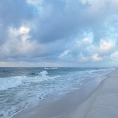 people are walking along the beach on a cloudy day