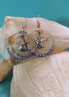 Ocean Tides and Waves Sapphire Blue Beaded Starfish Earrings. Blue glass seed beads strung on a silver colored hood. Starfish charm position in the center of hoop. These are a must for beach trip or any summer vacation event. Makes a great gift. Starfish-shaped Beaded Beach Jewelry, Handmade Blue Jewelry For Beach Season, Coastal Blue Beaded Jewelry, Blue Star Shaped Jewelry For Vacation, Blue Star Jewelry For Vacation, Blue Jewelry With Silver Beads For The Beach, Blue Starfish Charm Jewelry For Beach Season, Blue Starfish Charm Jewelry For The Beach, Starfish-shaped Beaded Jewelry For The Beach